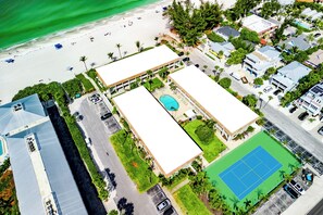 Luftaufnahme eines Anwesens an der Küste mit Swimmingpool, Tennisplatz und Zugang zum Strand.