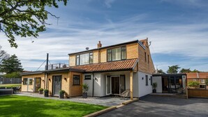 Et toetagers hus med en terrasse, en garage og en mindre tilbygning.