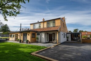 Ein zweistöckiges Haus mit Terrasse, Garage und einem kleinen Anbau.