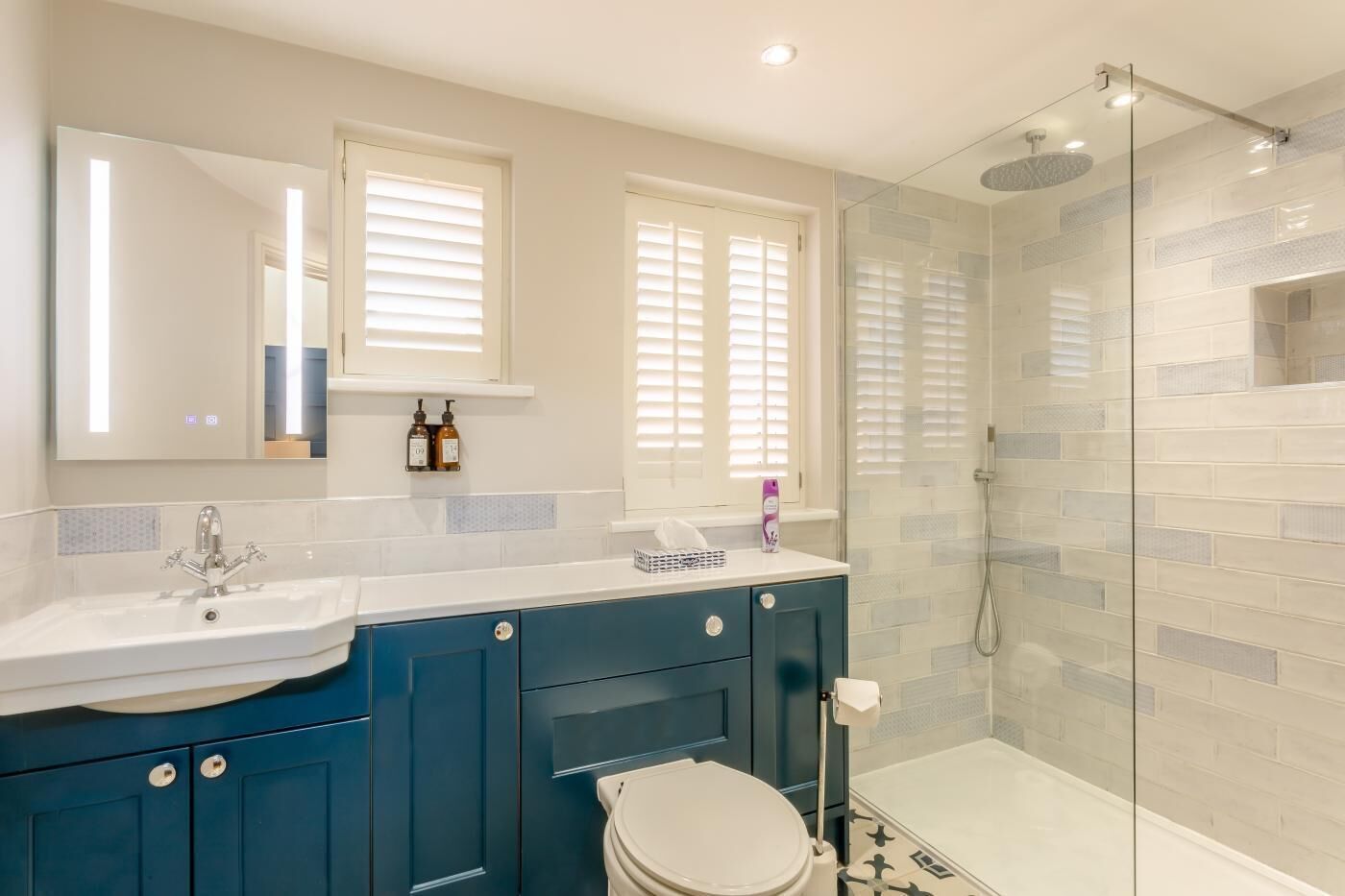 A modern bathroom with a glass-enclosed shower, a white sink, and a toilet.