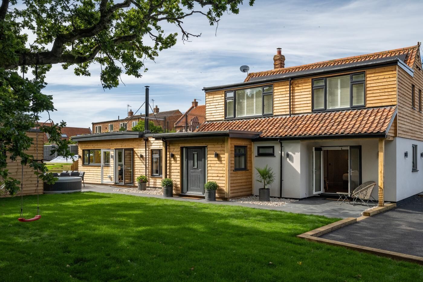 Ein modernes, zweistöckiges Haus mit gepflegtem Rasen, einer Terrassenanlage und einer Satellitenschüssel.