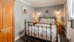 A bedroom with a wooden bed frame, two bedside tables with lamps, a wardrobe, and a picture on the wall. - 1 Bed in Appledore (oc-l45327) (Appledore)
