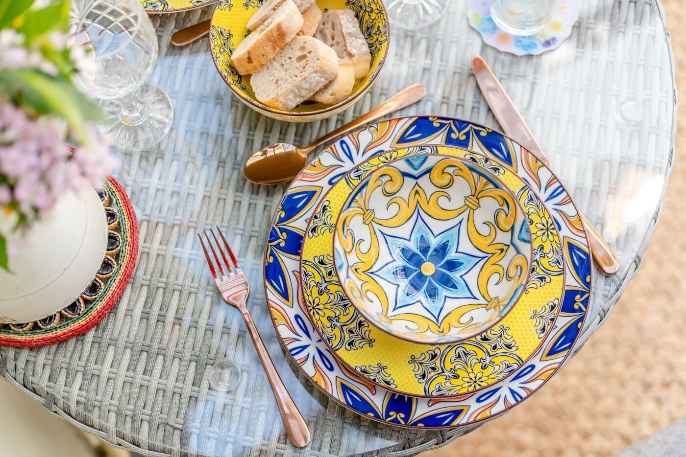 A table set with a colorful plate, a bowl of bread, and a fork.