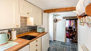 A kitchen with white cabinets, a wooden countertop, a toaster, and a stove. - 1 Bed in Appledore (oc-l45327) (Appledore)