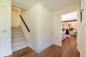Un escalier avec un mur en briques blanches, des marches en bois et une main courante.