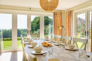 A dining area with a table set for four, large windows, and a view of greenery. - 6 Bed in Herons Ghyll (oc-t44940) (Heron's Ghyll)