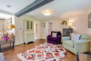 Een woonkamer met een bank, fauteuil, een kleed met patroon en een kast.