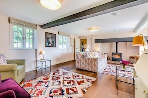 Een gezellige woonkamer met een open haard, een bank, een bijzettafeltje en een kamerbreed tapijt.
