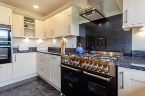 Une cuisine moderne avec des meubles blancs, une cuisinière en acier inoxydable et un four encastré.