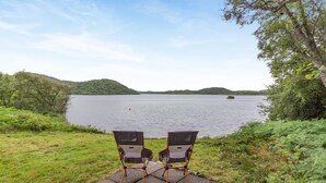 Two chairs facing a lake with a forested hill in the background. - 3 Bed in Lairg (oc-r44959) (Little Assynt)