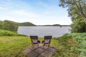 Two chairs facing a lake with a forested hill in the background. - 3 Bed in Lairg (oc-r44959) (Little Assynt)