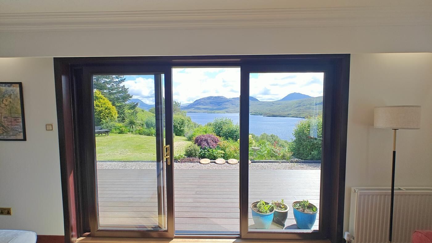 Ein Zimmer mit einer großen Schiebeglasdoor, die auf eine Terrasse mit Blumentöpfen führt.