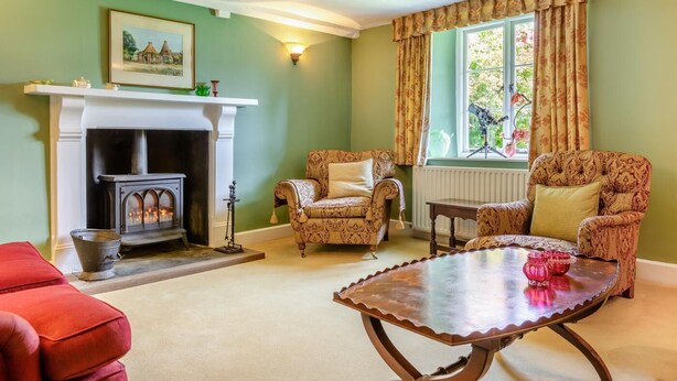 A room with a fireplace, patterned armchairs, a wooden coffee table, and a window with curtains. - 5 Bed in George Nympton (oc-t40683) (George Nympton)