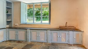A kitchen with a stone floor, a window with a view of greenery, and a wicker basket on the counter. - 5 Bed in George Nympton (oc-t40683) (George Nympton)