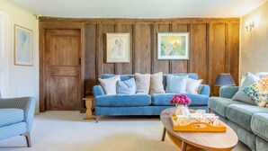 A living room with a blue sofa, a wooden coffee table, and a lamp. - 5 Bed in George Nympton (oc-t40683) (George Nympton)