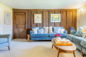 Ein Wohnzimmer mit einem blauen Sofa, einem Holztisch und einer Lampe.
