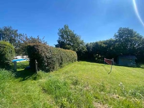 A grassy outdoor area with a hedge, a red object, and a blue structure in the background. - 3 Bed in Overton (oc-b45279) (Overton)