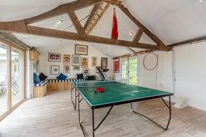 Ein Tischtennistisch in einem Raum mit Holzbalken, einer gepolsterten Bank und gerahmten Bildern an den Wänden.