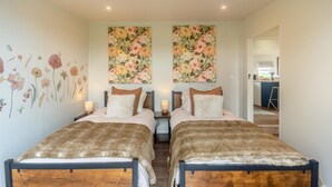 A double room with two beds, floral wall art, and a visible kitchen area. - 2 Bed in Overton (oc-k45280) (Overton)