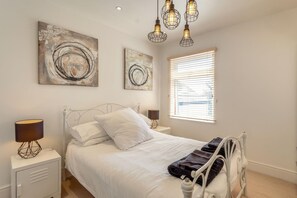 Ein Schlafzimmer mit einem Bett, Nachttischlampen und abstrakter Wandkunst.