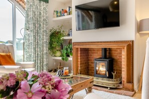 Ein Wohnzimmer mit Kamin, Flachbildfernseher und Bücherregal.