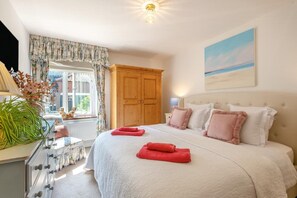 A bedroom with a large bed, a wooden wardrobe, a window with curtains, and a painting on the wall. - 2 Bed in Great Witchingham (oc-p45227) (Great Witchingham)