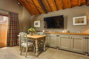 A dining area with a wooden table, chairs, and a vase of flowers.