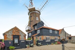 A traditional windmill with a brick tower and adjacent buildings with stone and wooden facades.