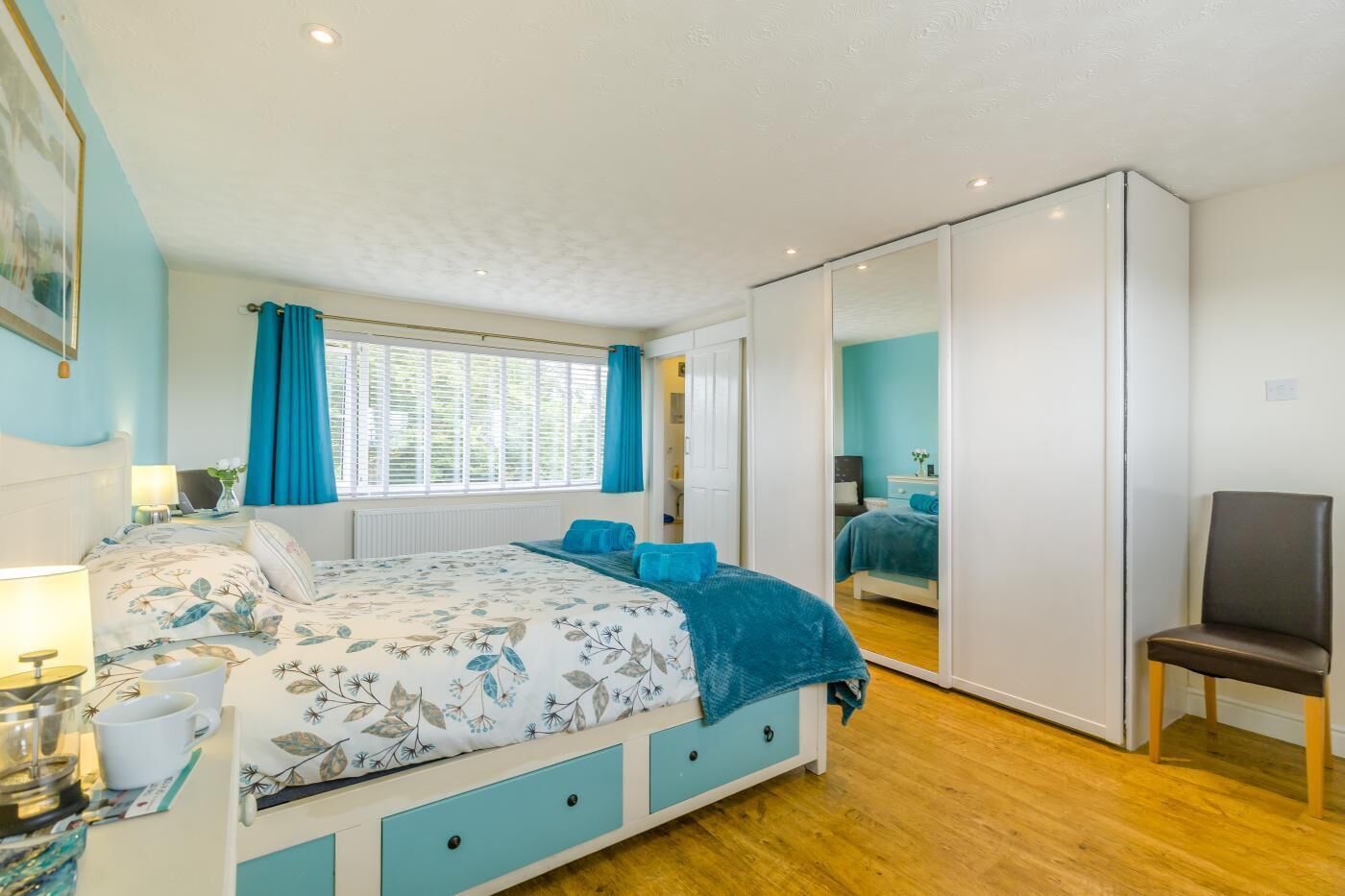 A bedroom with a bed, bedside table, lamp, and a wardrobe.