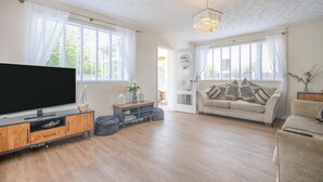A spacious living room with a flat-screen TV, a sofa, a coffee table, and a chandelier. - 3 Bed in Sheringham (oc-s44832) (Sheringham)