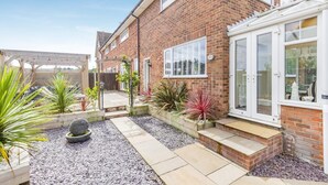A brick house with a patio, garden, and a covered outdoor seating area. - 3 Bed in Sheringham (oc-s44832) (Sheringham)