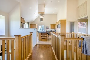 Eine moderne Küche mit Holzschränken, einer zentralen Kochinsel mit Barhocker und Blick auf den Garten durch ein Fenster.