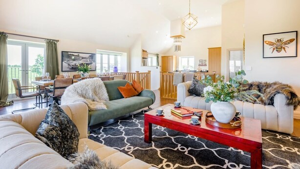 Ein großzügiges Wohnzimmer mit Essbereich, einer Küche und einem Balkon.