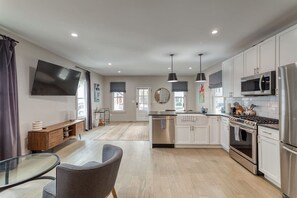 Una cocina moderna con armarios blancos, electrodomésticos de acero inoxidable e iluminación colgante.