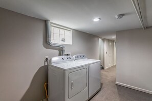 A laundry room with a stacked washer and dryer, a vent pipe, and a hallway leading to a door.