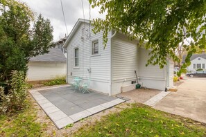 A small, single-story house with a patio area, a small table, and chairs.