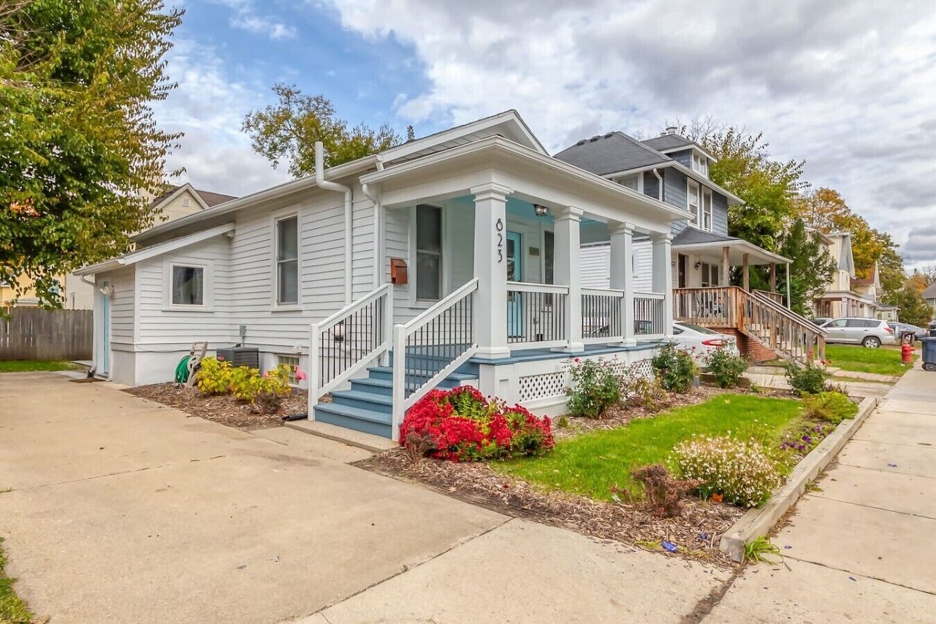 A two-story residential house with a front porch, a staircase, and a well-maintained lawn.