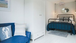 Et soveværelse med seng, skab, sofa og en mindre måtte.