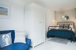 A bedroom with a bed, a wardrobe, a sofa, and a small rug. - 2 Bed in Mousehole (oc-b584374) (Mousehole)