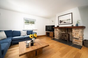 A living room with a sofa, a coffee table with a vase of sunflowers, a fireplace, and a television.