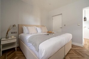 A bedroom with a bed, bedside table, lamp, and a door. - 2 Bed in Bude (oc-b588790) (Bude)