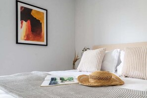 A neatly made bed with a striped pillow, a straw hat, and a magazine on a textured blanket. - 2 Bed in Bude (oc-b588790) (Bude)
