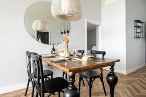 A dining area with a wooden table, black chairs, and a large mirror on the wall. - 2 Bed in Bude (oc-b588790) (Bude)
