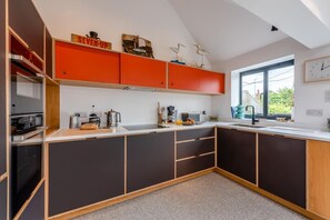 A modern kitchen with a large island, built-in appliances, and a window providing natural light. - 2 Bed in Rye (oc-s43273) (Rye Harbour)