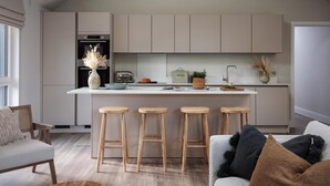 A modern kitchen with a central island, bar stools, and a dining area with a sofa. - 2 Bed in Padstow (oc-b623759) (Padstow)
