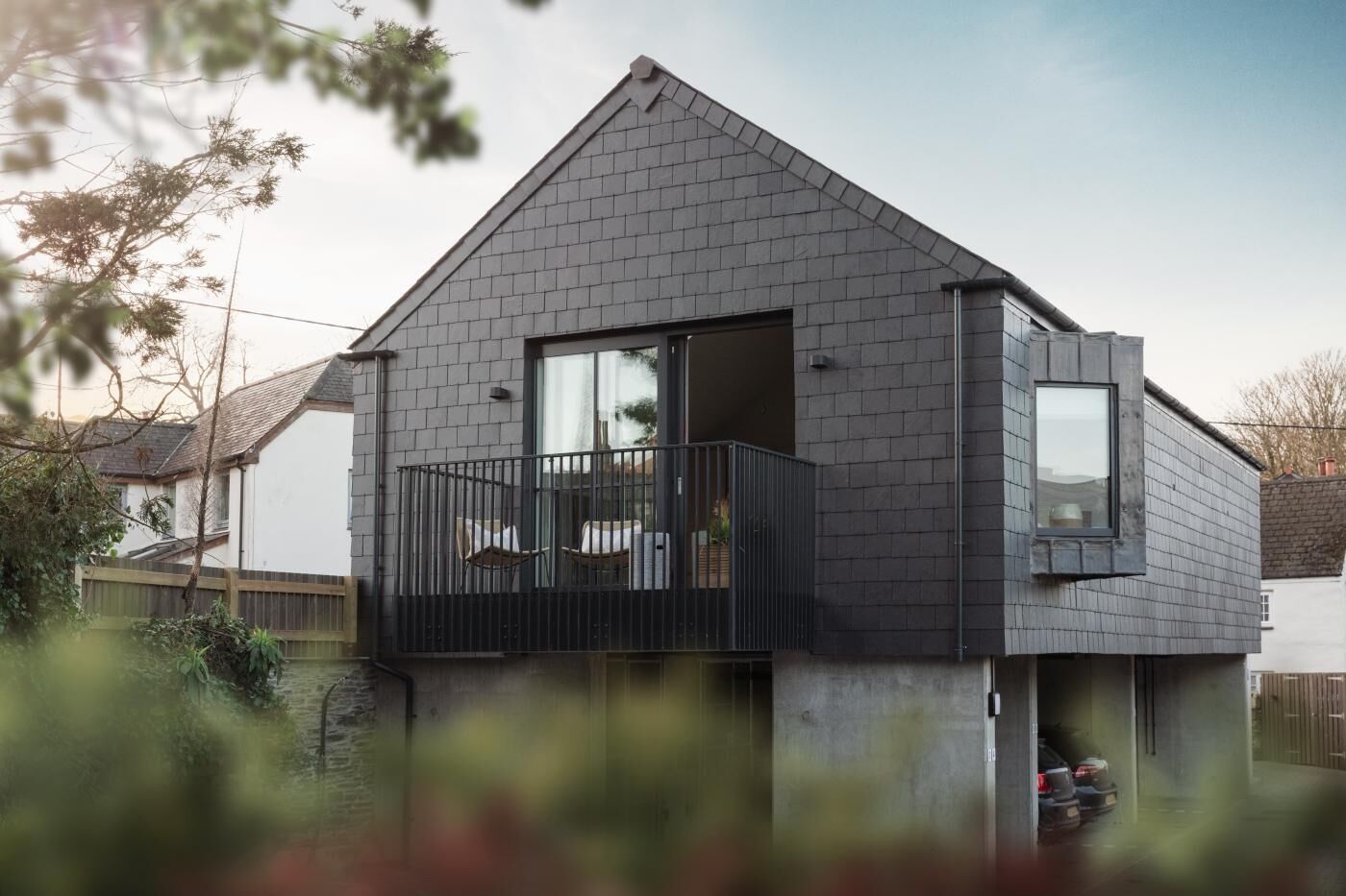 Ein modernes, zweistöckiges Haus mit Balkon, Garage und auffälligem Auffahrt.