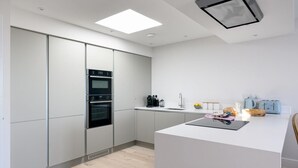 Een moderne keuken met een centraal eiland, inbouwovens en een minimalistisch design.