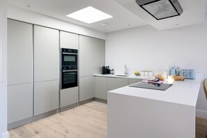 Eine moderne Küche mit einer zentralen Kochinsel, eingebauten Backöfen und einem minimalistischen Design.
