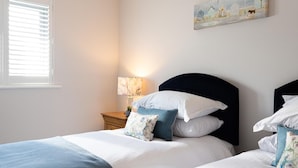 Een slaapkamer met twee bedden, een nachtkastje, een lamp en een schilderij aan de muur.