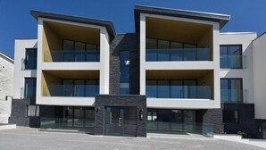 Un moderno edificio residenziale a più piani con ampie finestre e un ingresso centrale.